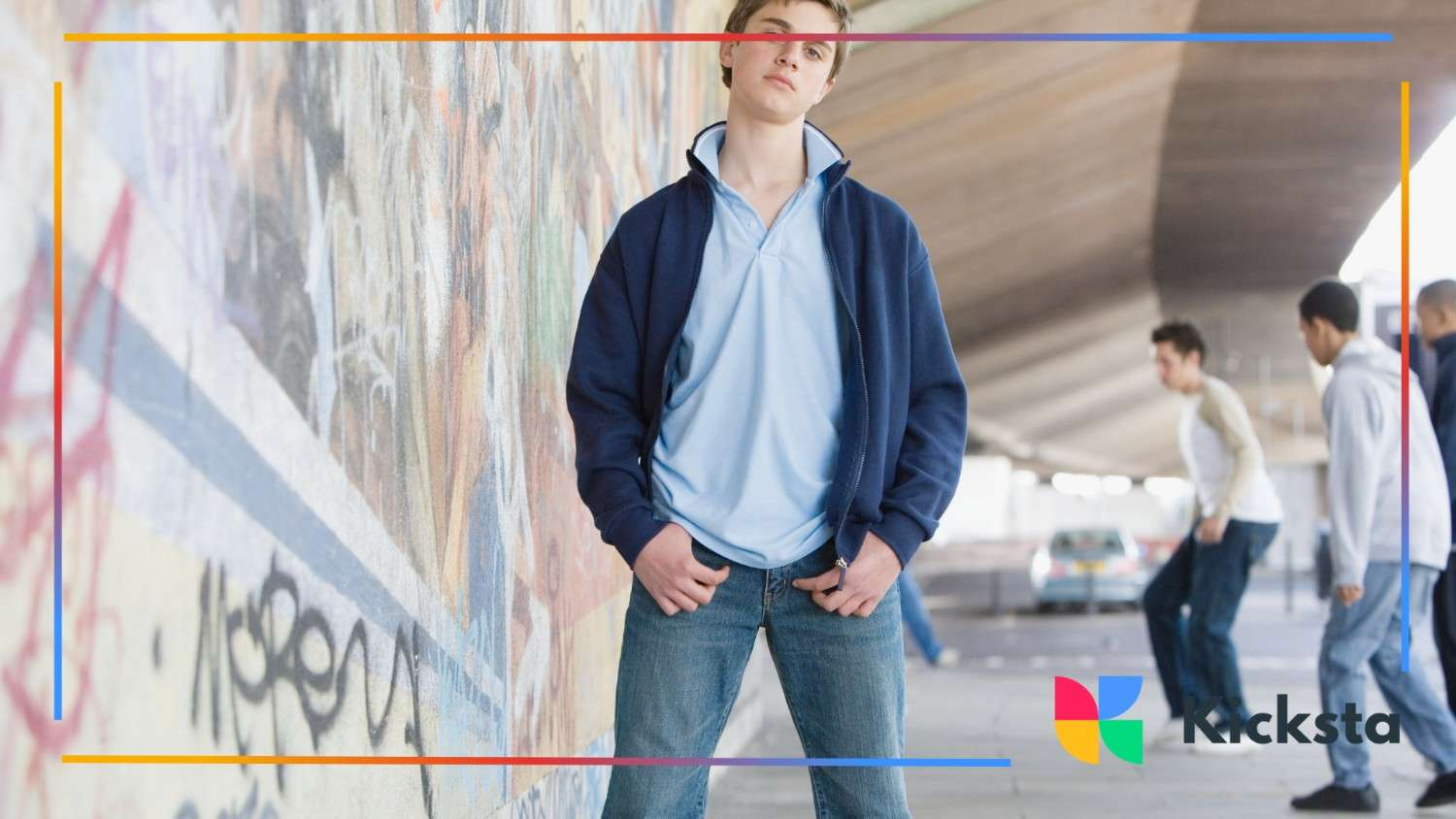 Teen boy standing confidently in front of graffiti wall