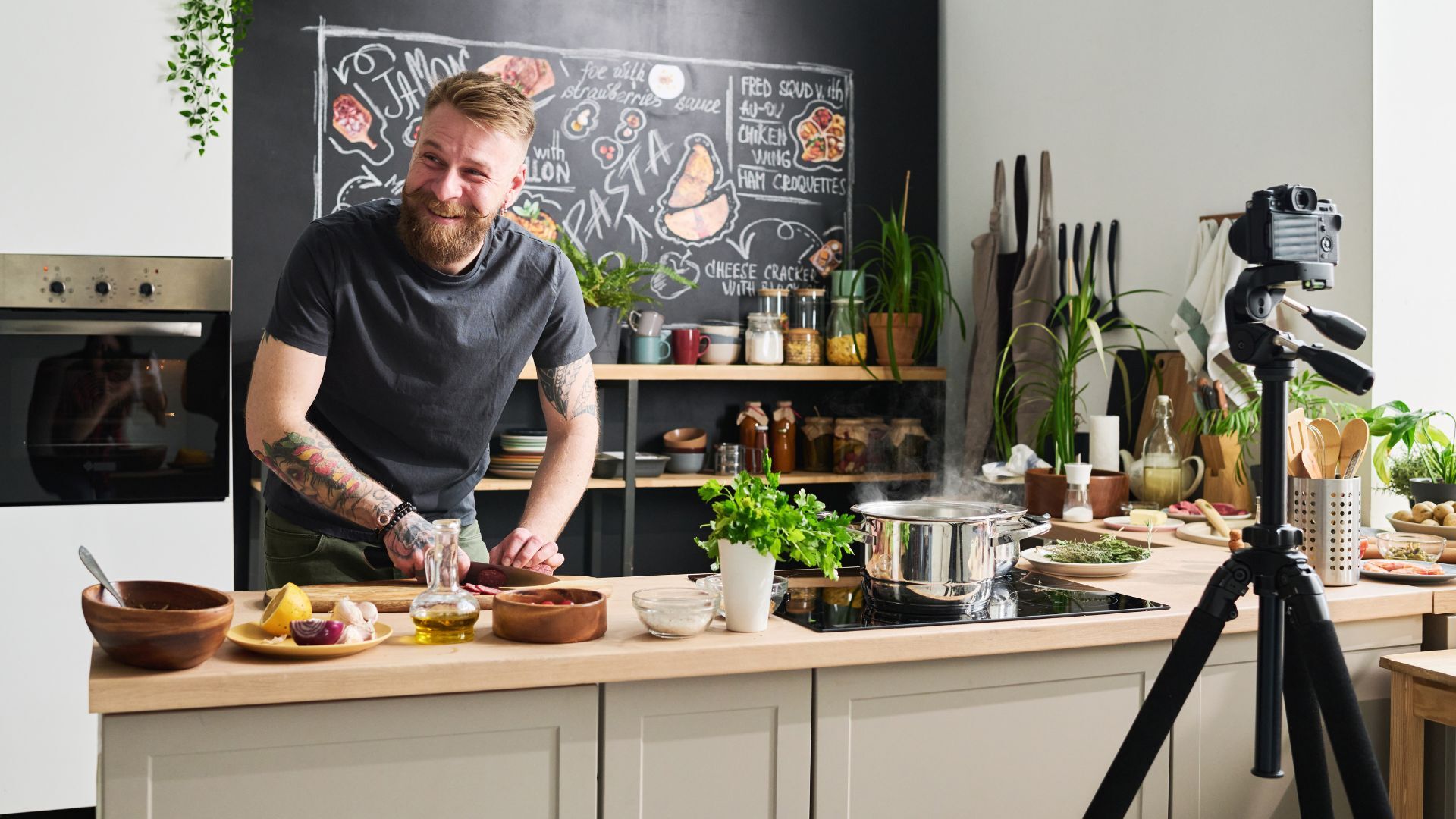 Bearded man smiling while cooking in modern kitchen during video shoot