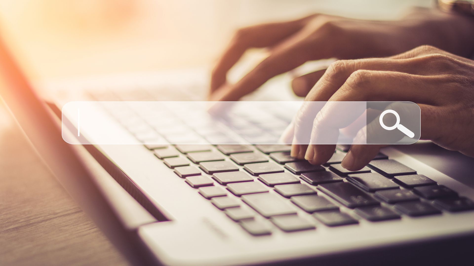 Person typing on a laptop keyboard with a transparent search bar overlay and magnifying glass icon.