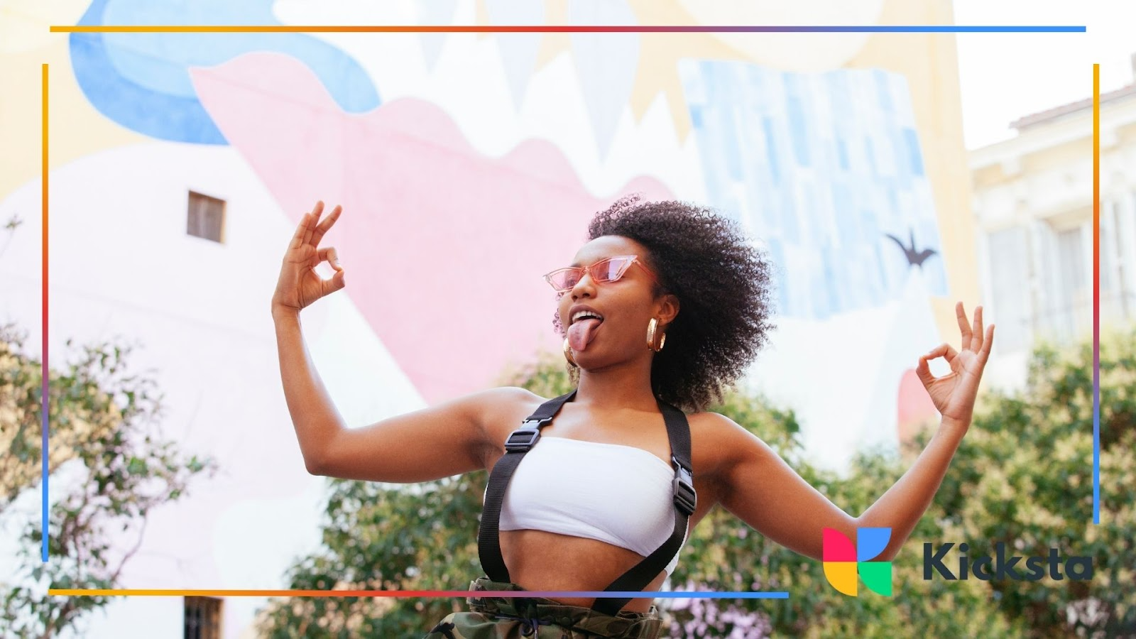 A stylish young woman striking a fun pose in front of a colorful mural