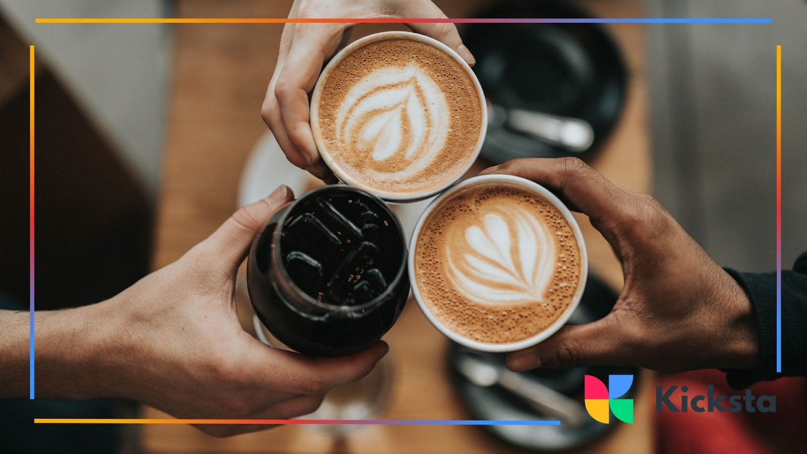 Three hands holding up coffee cups and a glass of iced drink for a toast
