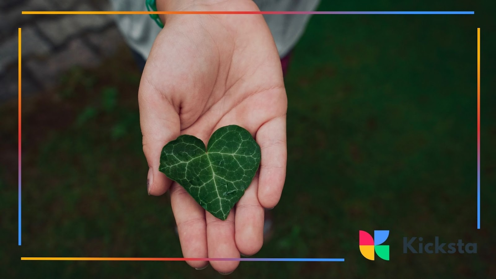 A green ivy leaf shaped like a heart held in an open palm