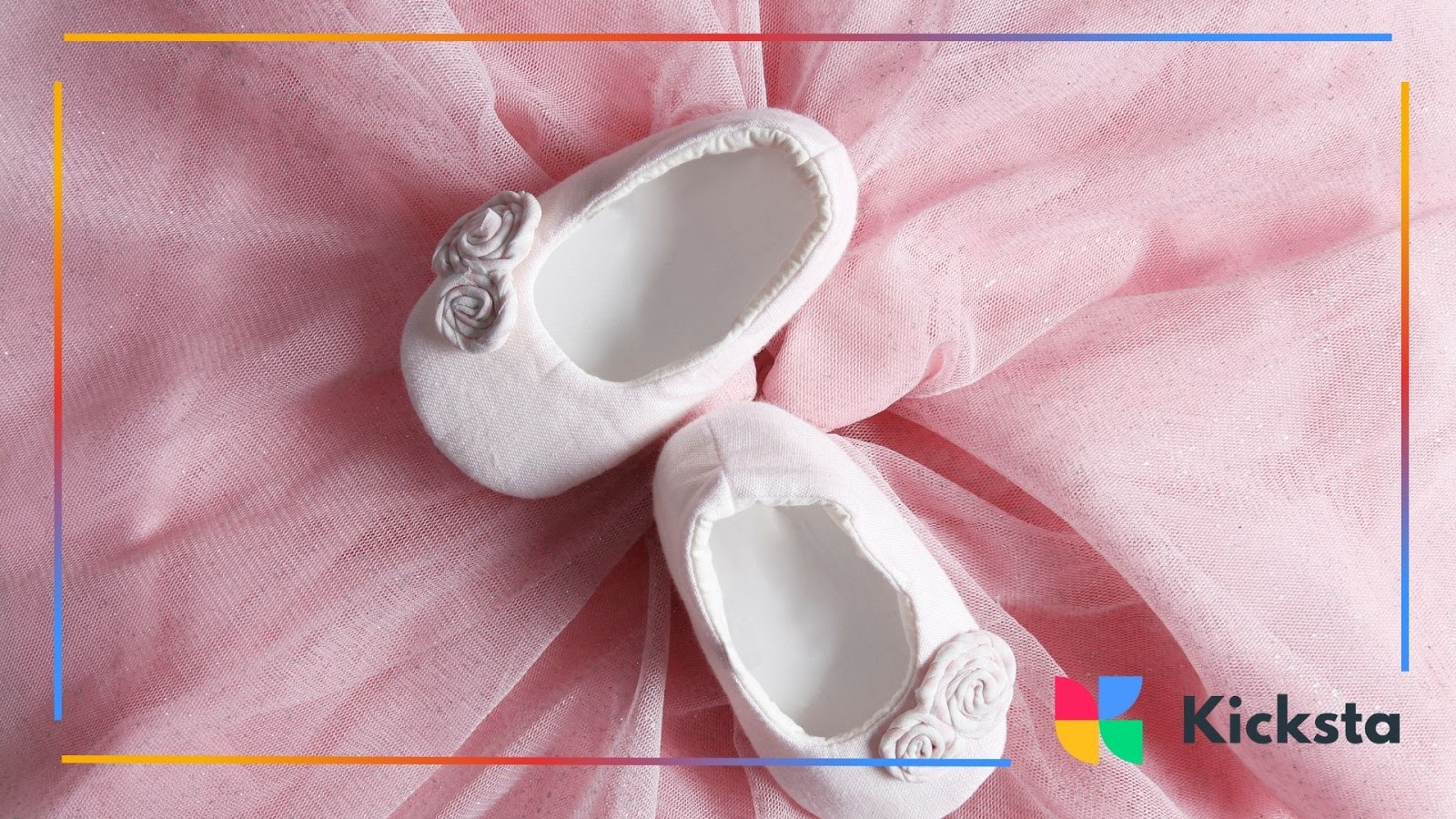 A pair of pink baby shoes resting on soft pink tulle
