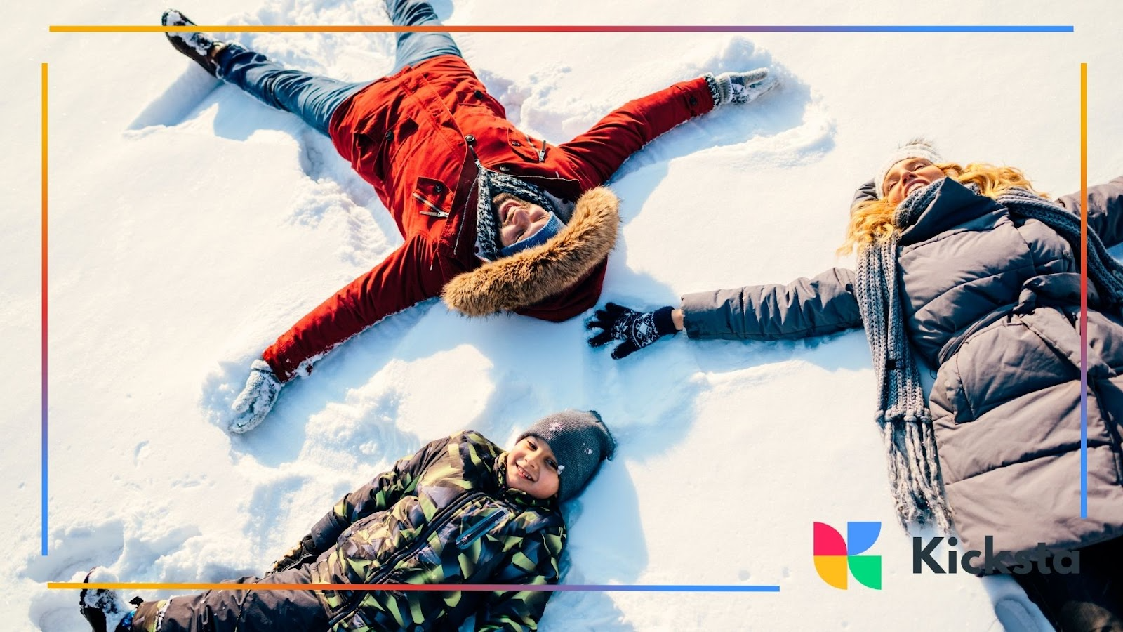 Three people lying in snow, smiling and making snow angels