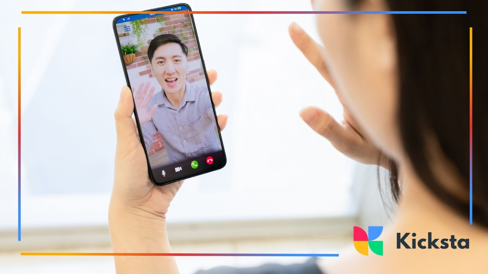 Close-up of a woman video chatting on her phone with a man waving.