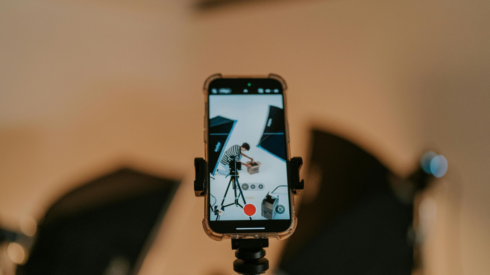 Smartphone on a tripod recording a musician in a professional studio with lights.