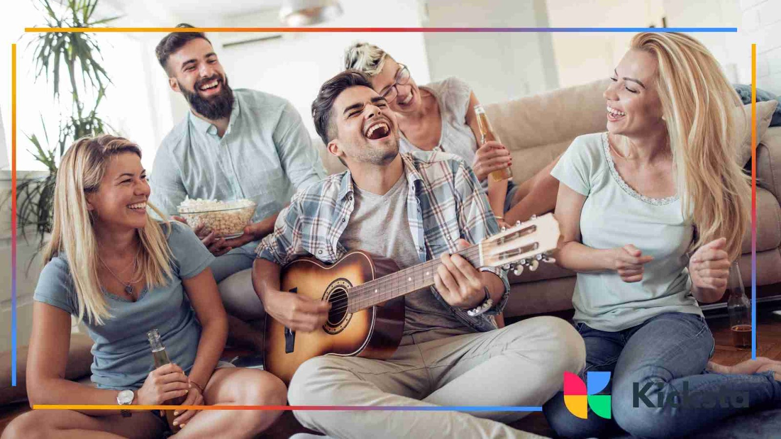 Group of friends laughing and singing while one plays guitar indoors.