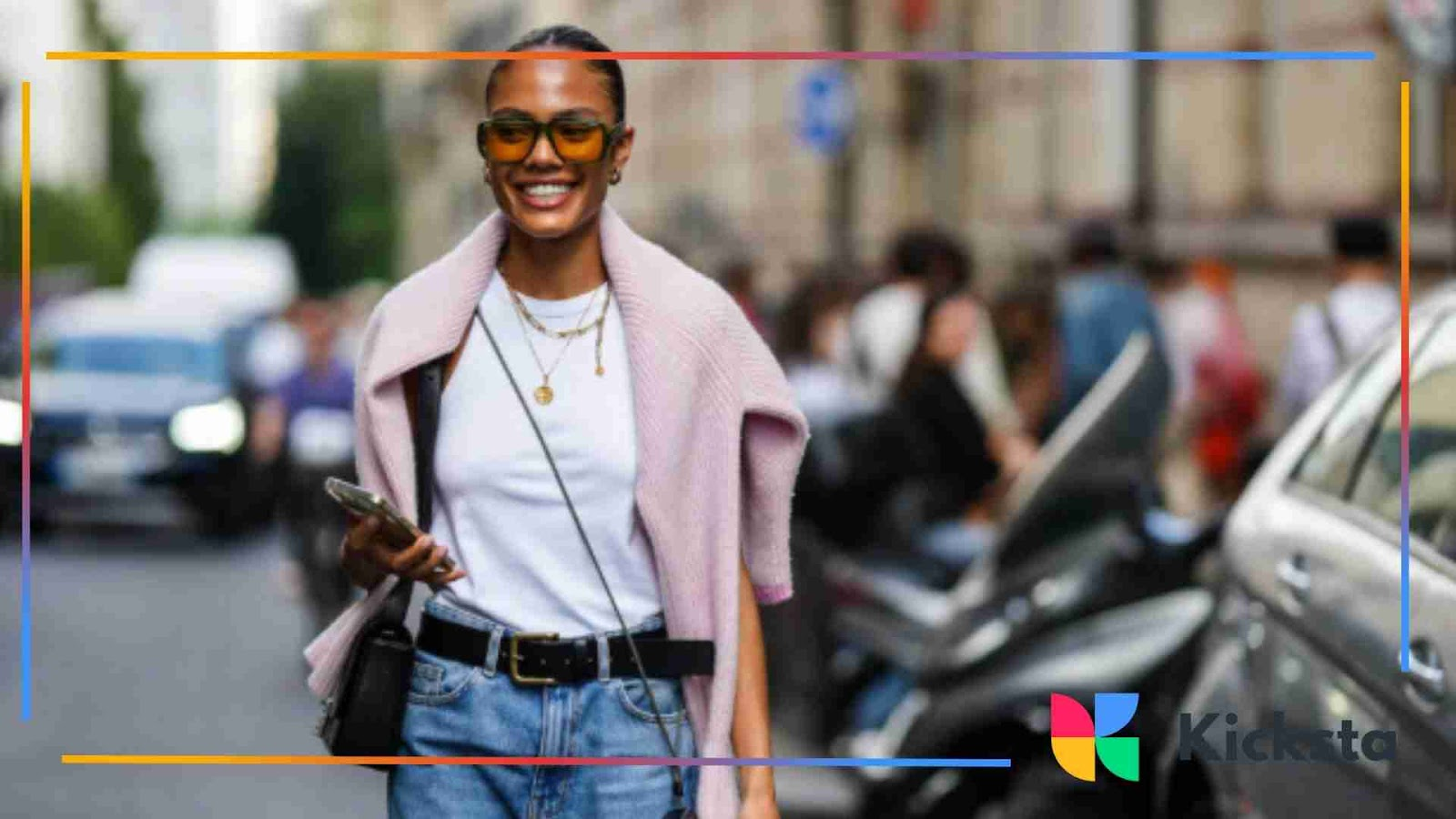 Fashionable woman smiling in city street style outfit with sunglasses and layered jewelry showcasing normcore aesthetic.