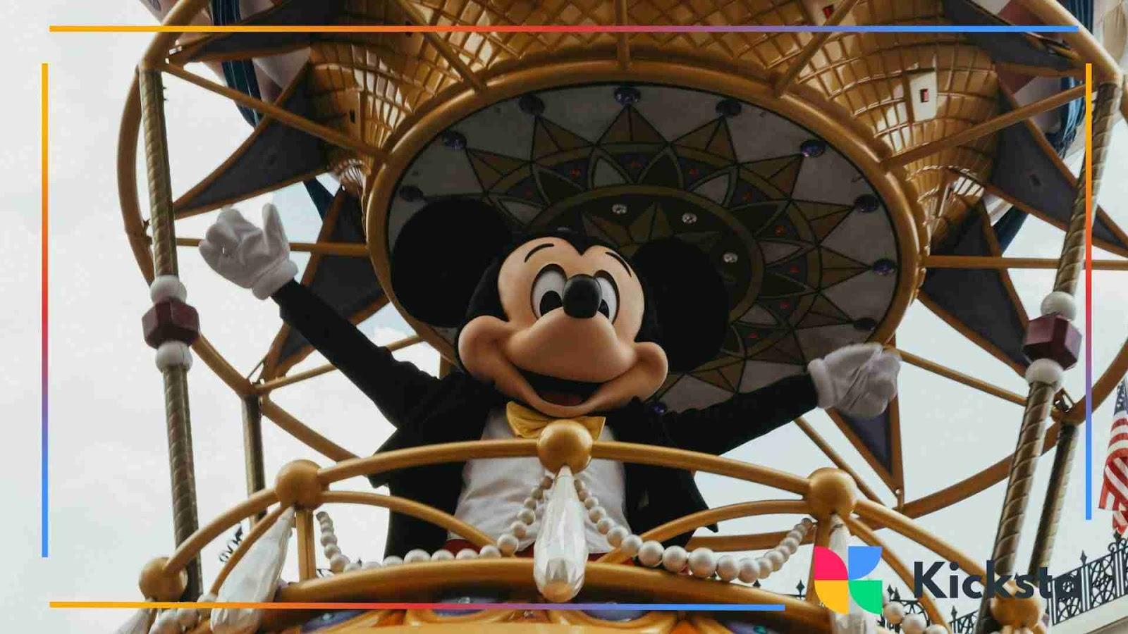 Mickey Mouse mascot waving happily from a decorated parade float