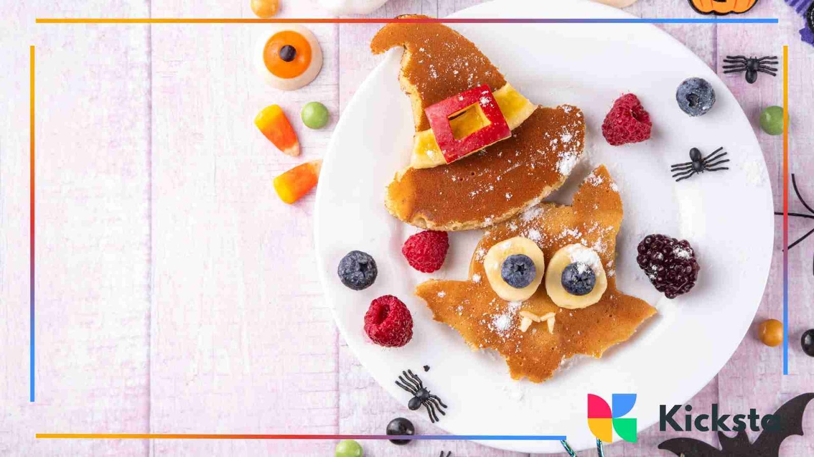 Halloween-themed pancakes shaped like a witch hat and bat with fruit toppings