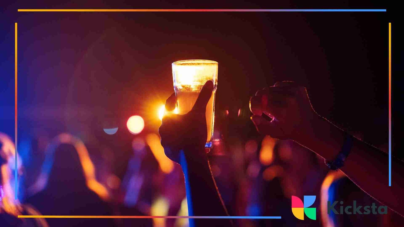 Hands holding up a glowing drink at a night party with colorful lights in the background.