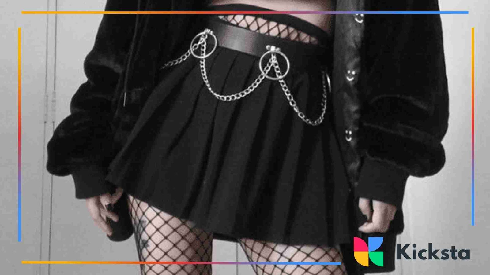 Black pleated skirt with fishnet tights and chain belt, showcasing grunge-inspired alt fashion.