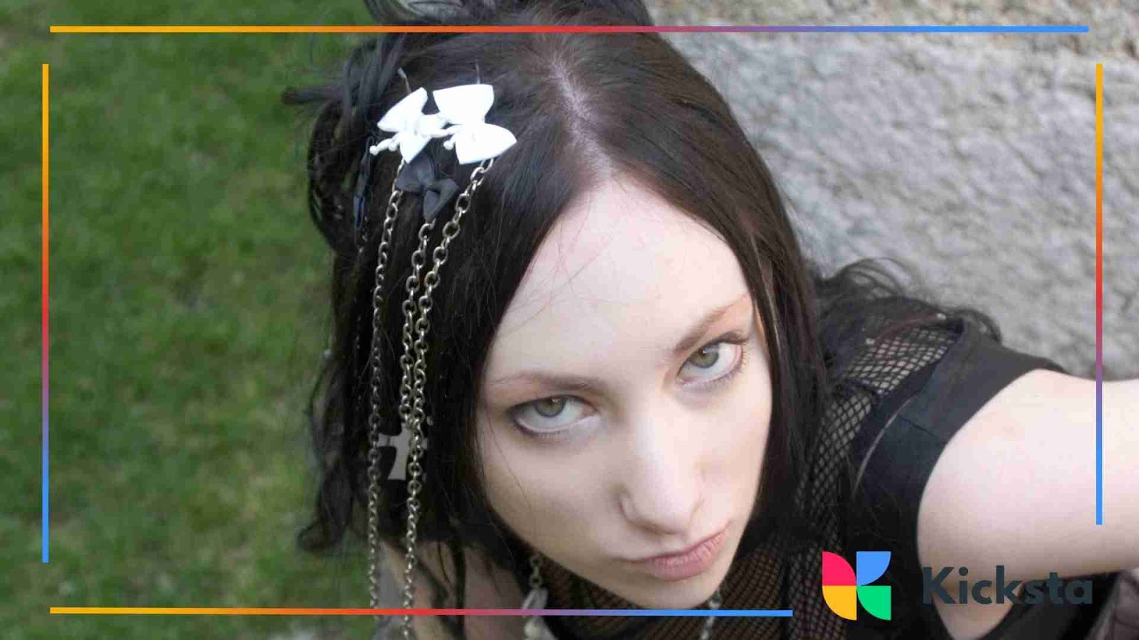 Close-up of a person with dark hair, pale skin, and dramatic eyeliner, styled with gothic-inspired accessories.