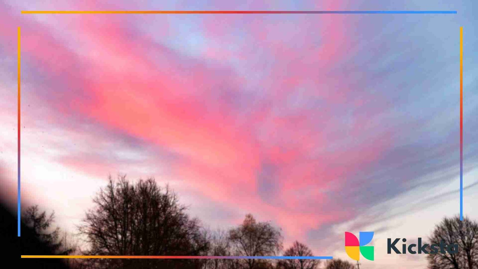 Pink clouds spread across the sky above treetops at sunset.
