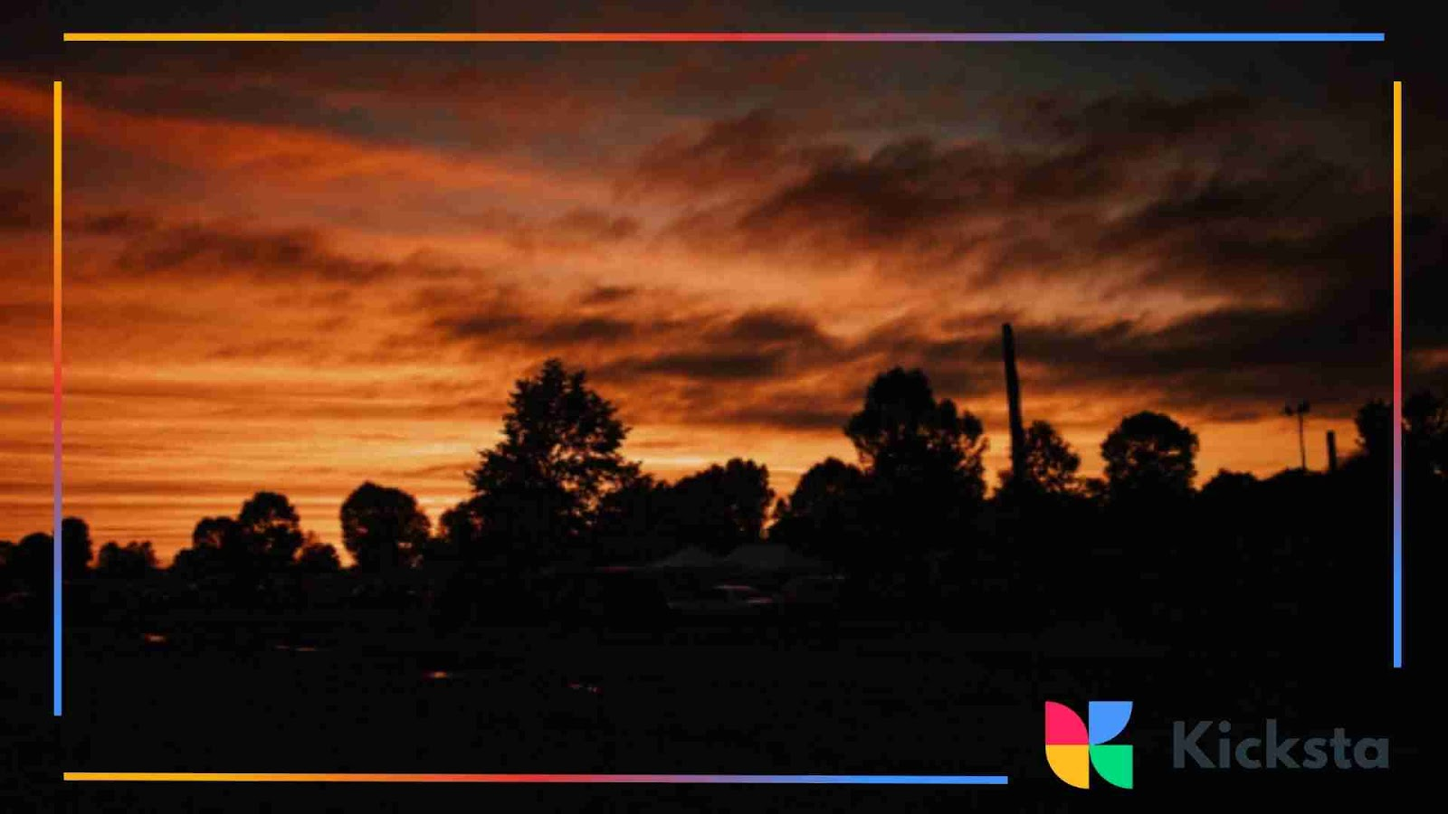A dark orange sunset with silhouetted trees in the foreground.