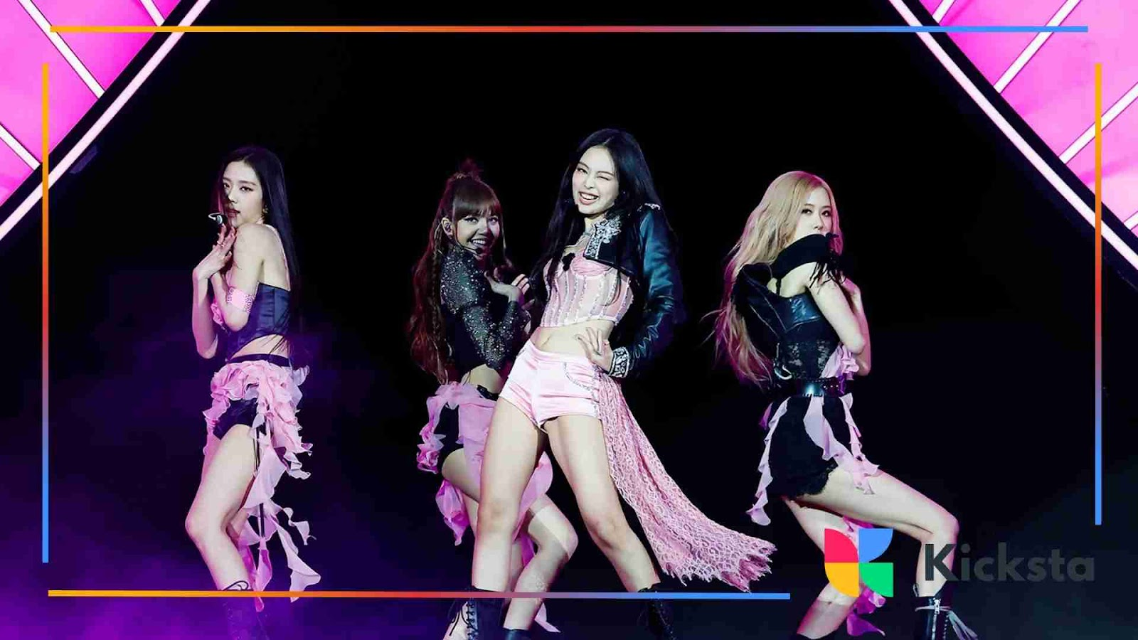 Blackpink performing live on stage in coordinated pink and black outfits.