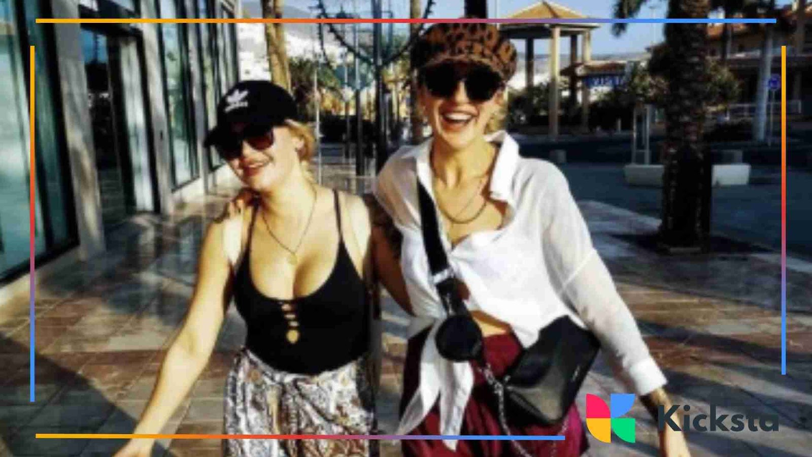 Two women wearing sunglasses and hats, walking outside together on a sunny day.