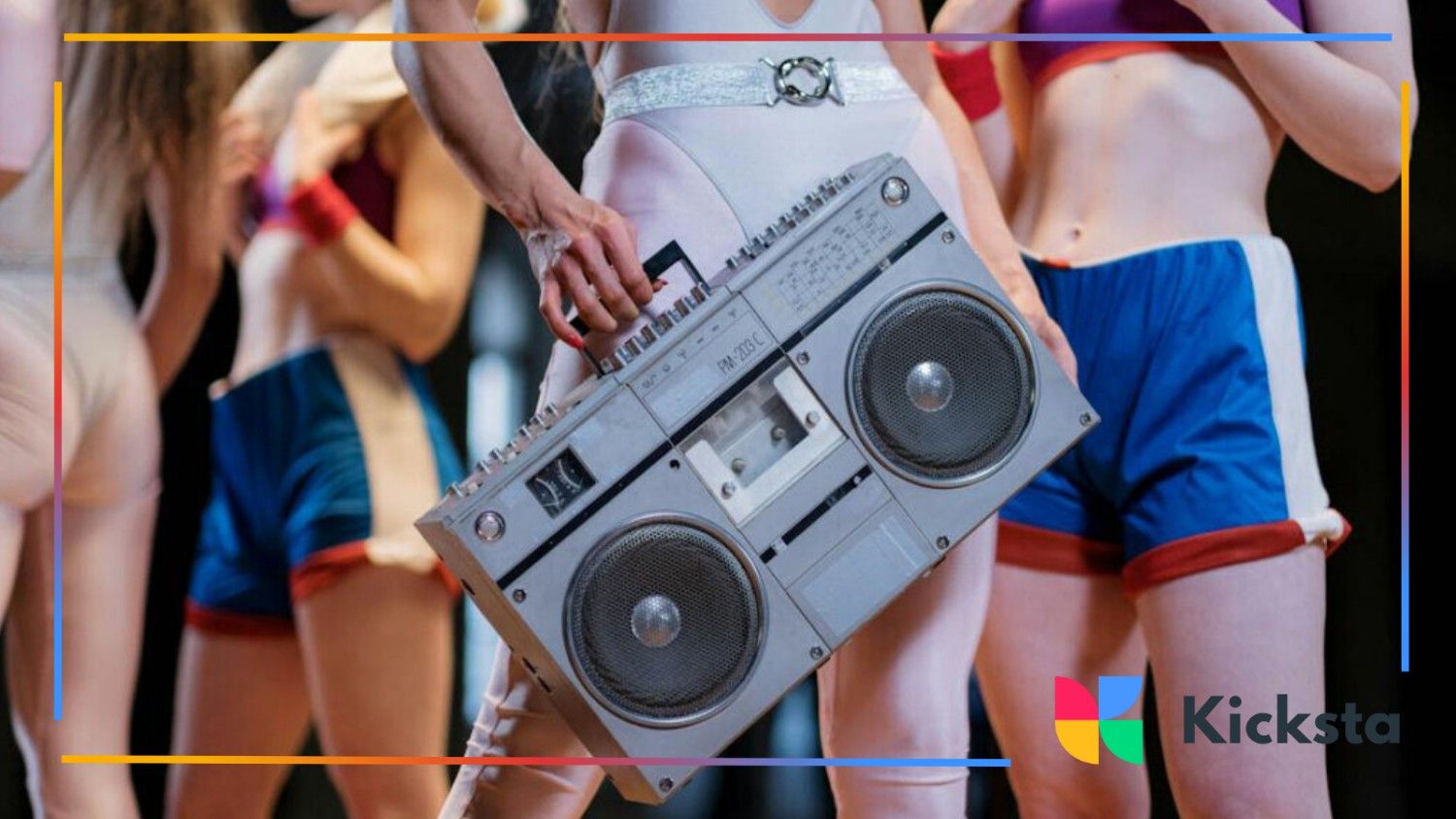Close-up of dancers in retro workout outfits, one holding a silver boombox