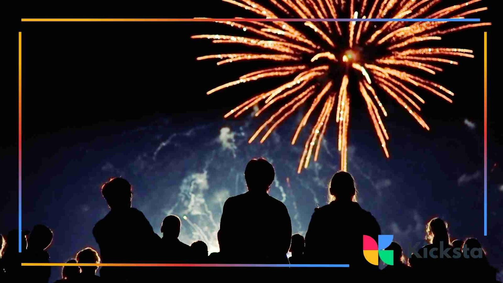 A crowd of people watching a large fireworks display lighting up the night sky