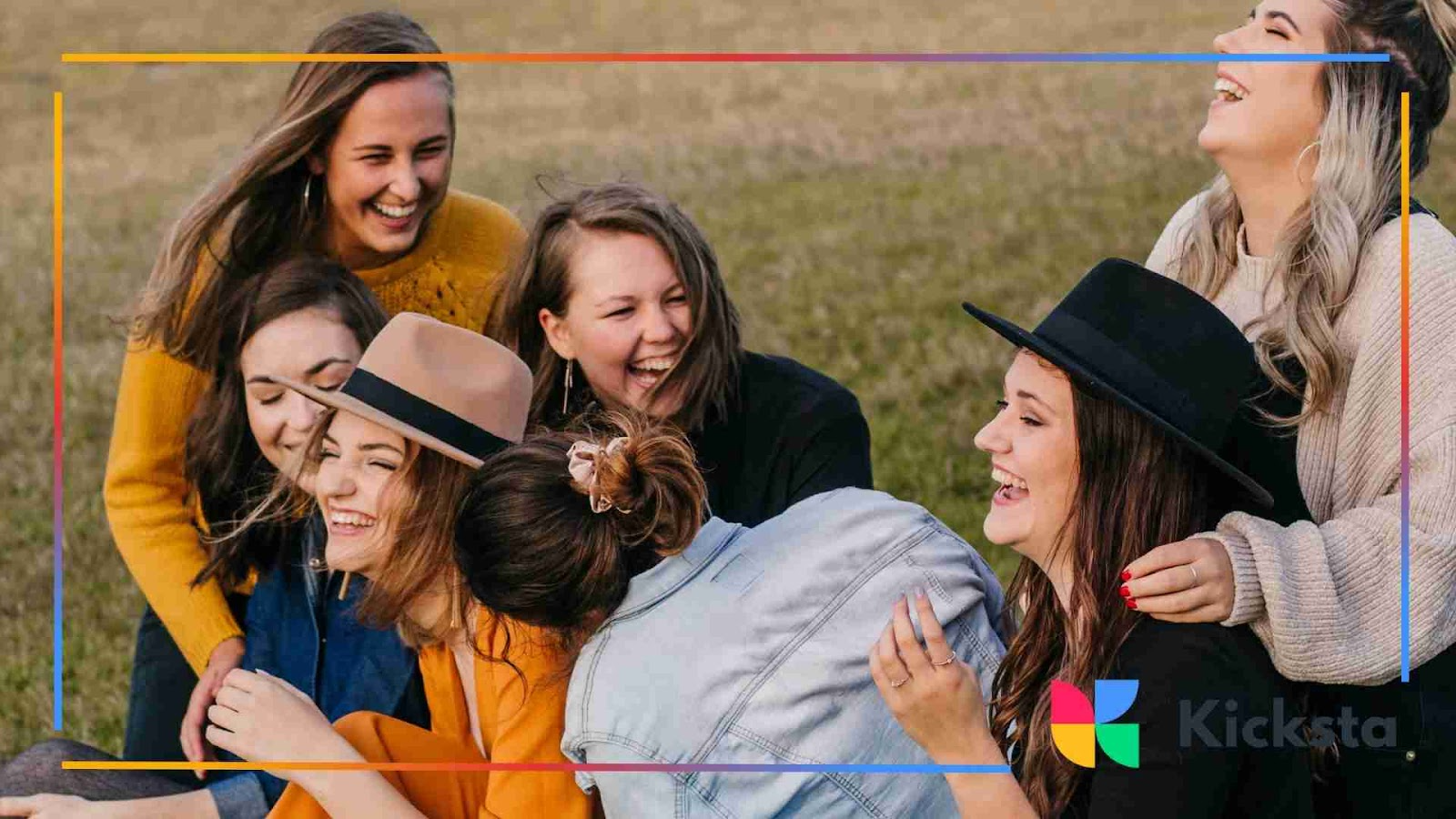 A group of young women sitting together outdoors, laughing and enjoying each other’s company on a grassy field