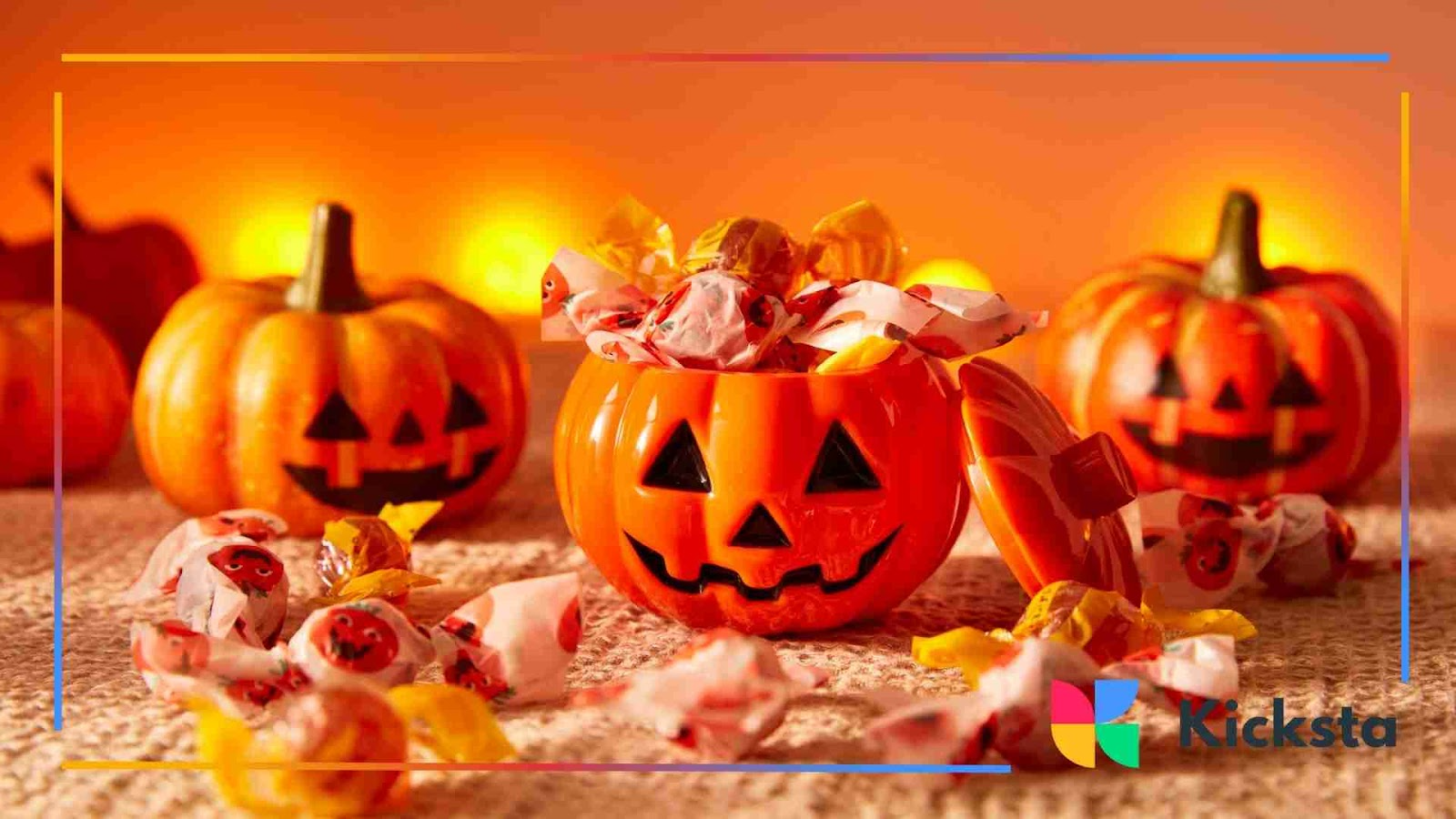 Halloween decorations with pumpkin-shaped candy buckets filled with colorful sweets on a festive orange background