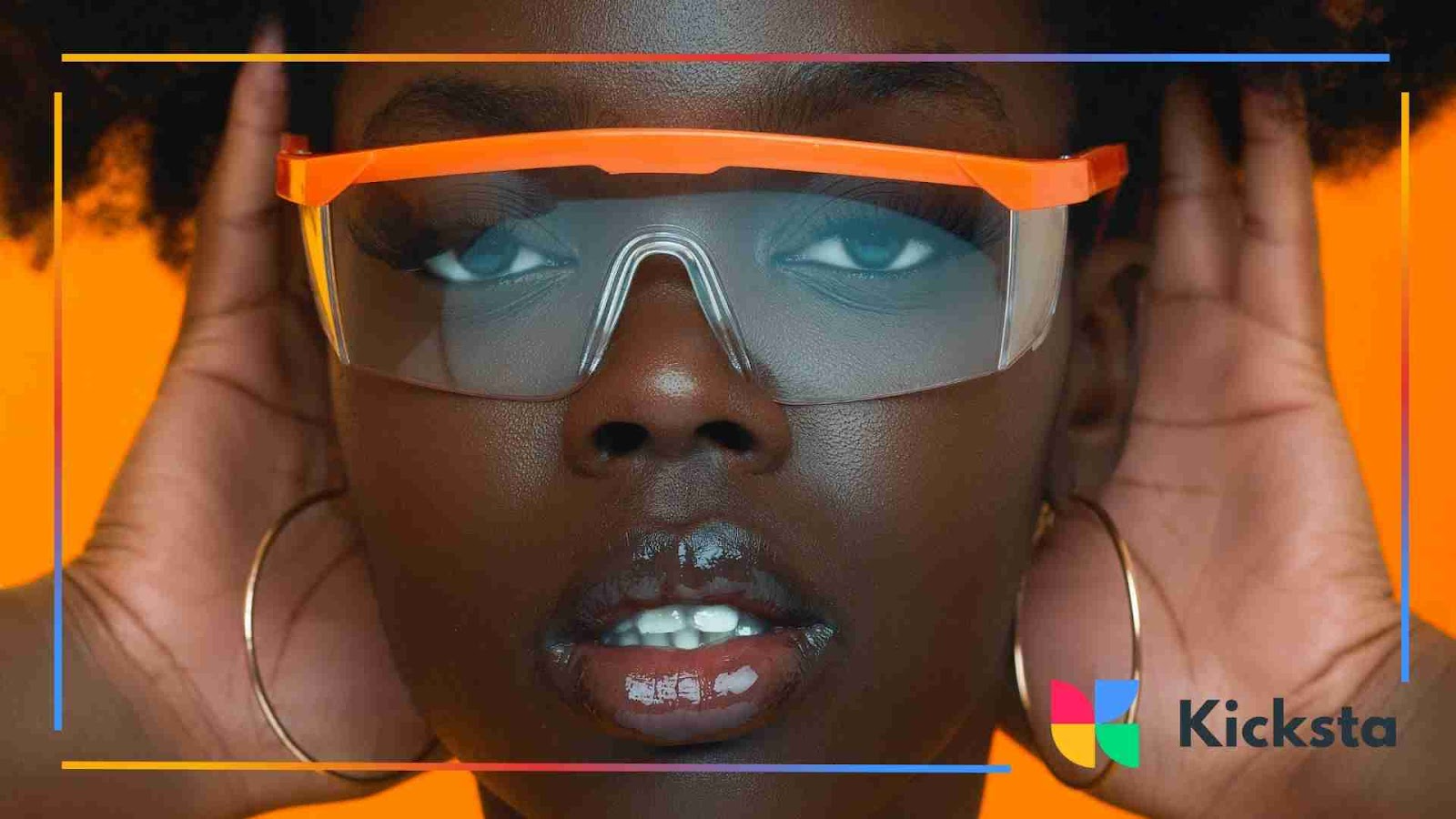 Close-up portrait of a person wearing orange visor sunglasses with hoop earrings against an orange background