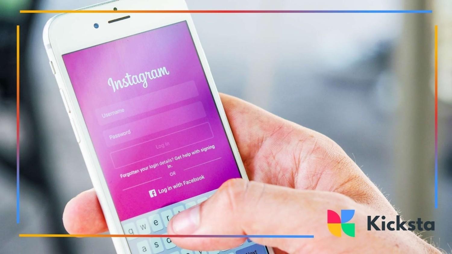 Close-up of a person holding a smartphone showing the Instagram login screen with a pink gradient background