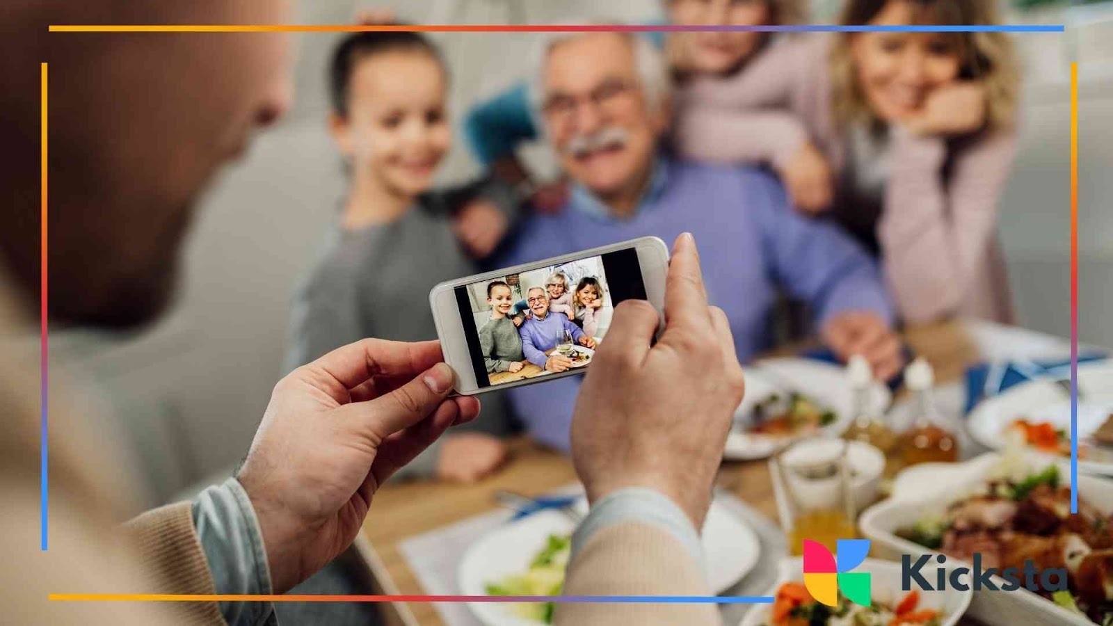 Person taking a smartphone photo of a smiling family gathered around a dinner tabl