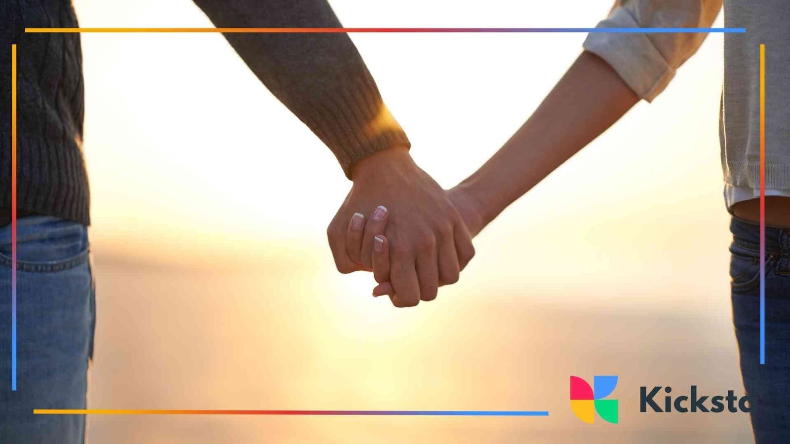 Close-up of two people holding hands at sunset, with warm sunlight shining between them.