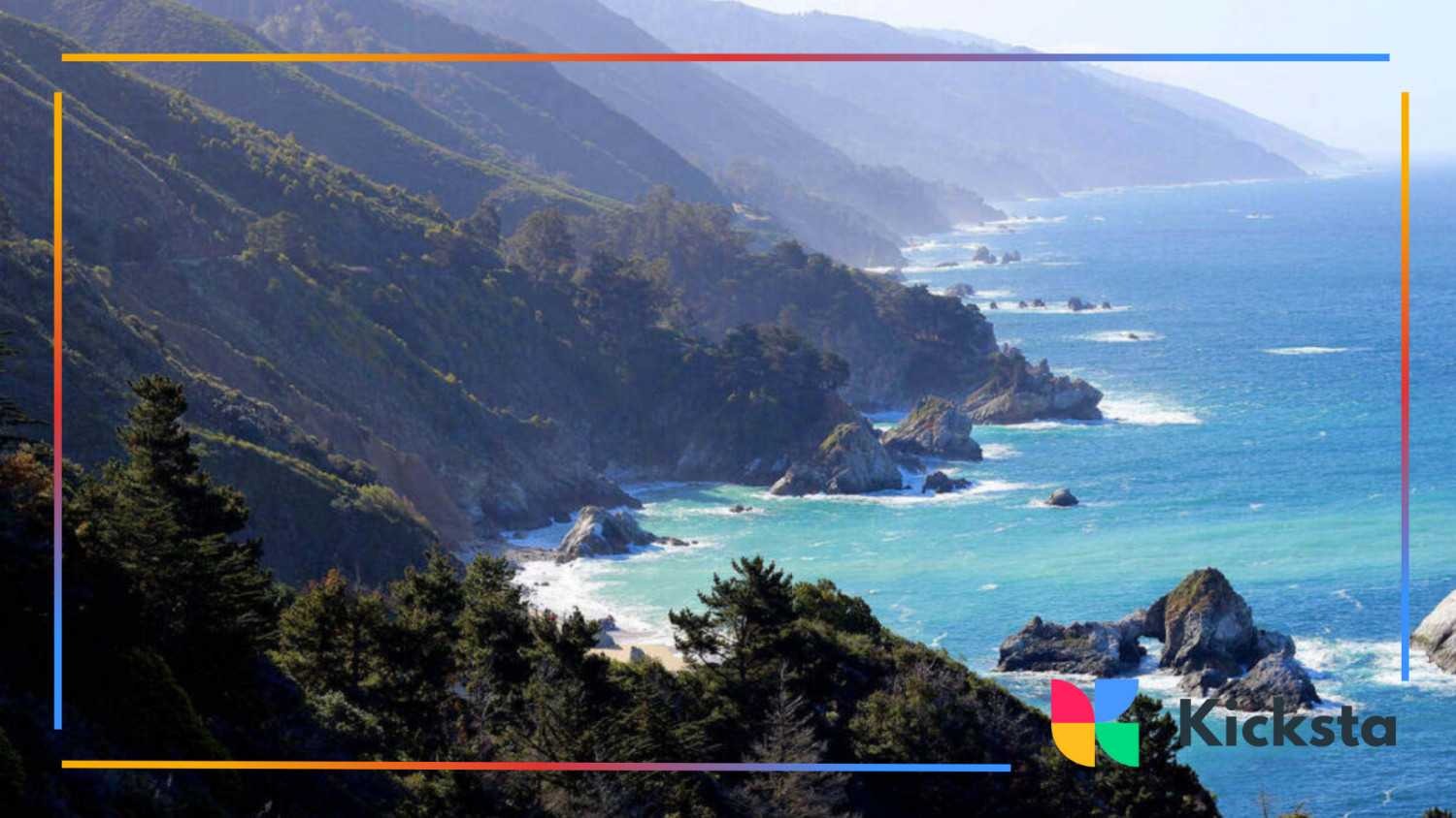 Dramatic coastal cliffs of Big Sur with turquoise ocean waves crashing below and forested hillsides above.