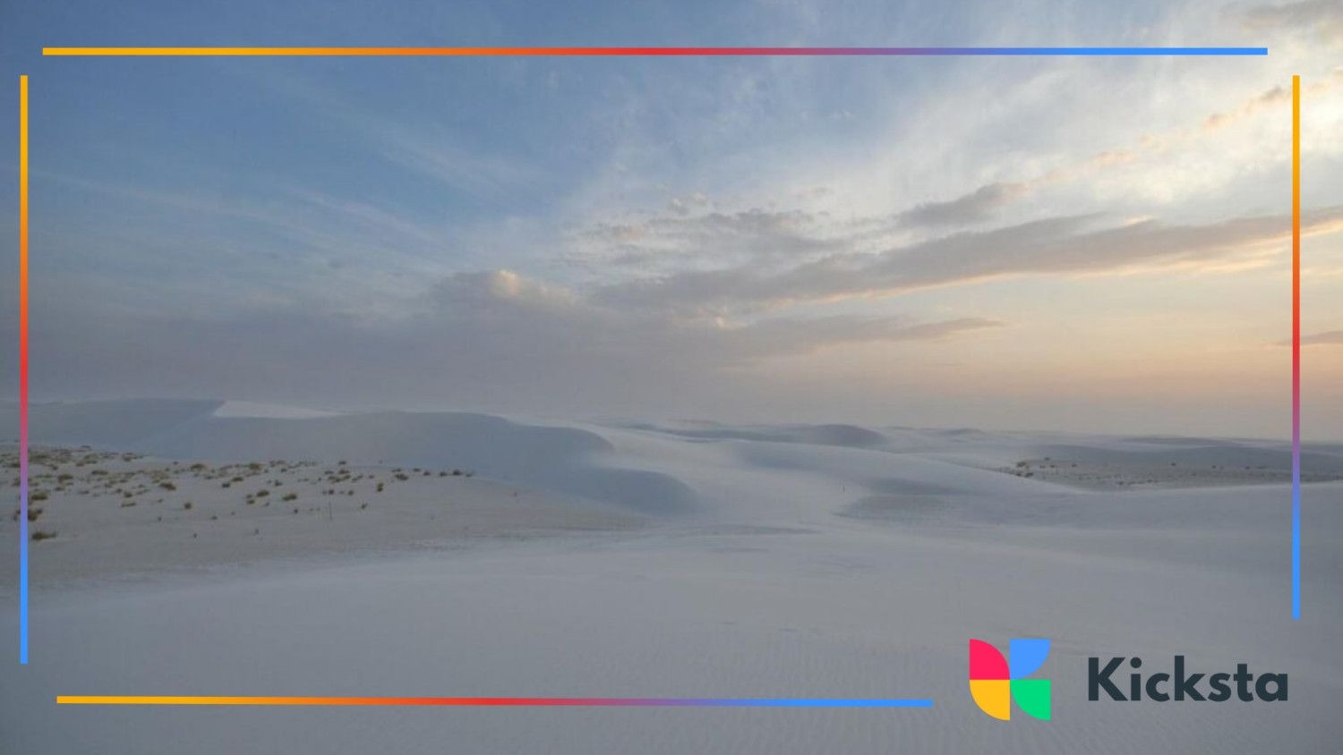 Vast landscape of white sand dunes under a cloudy blue sky at sunset