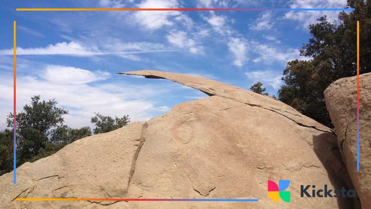 Natural rock formation known as Potato Chip Rock, a thin ledge jutting out against a bright blue sky.