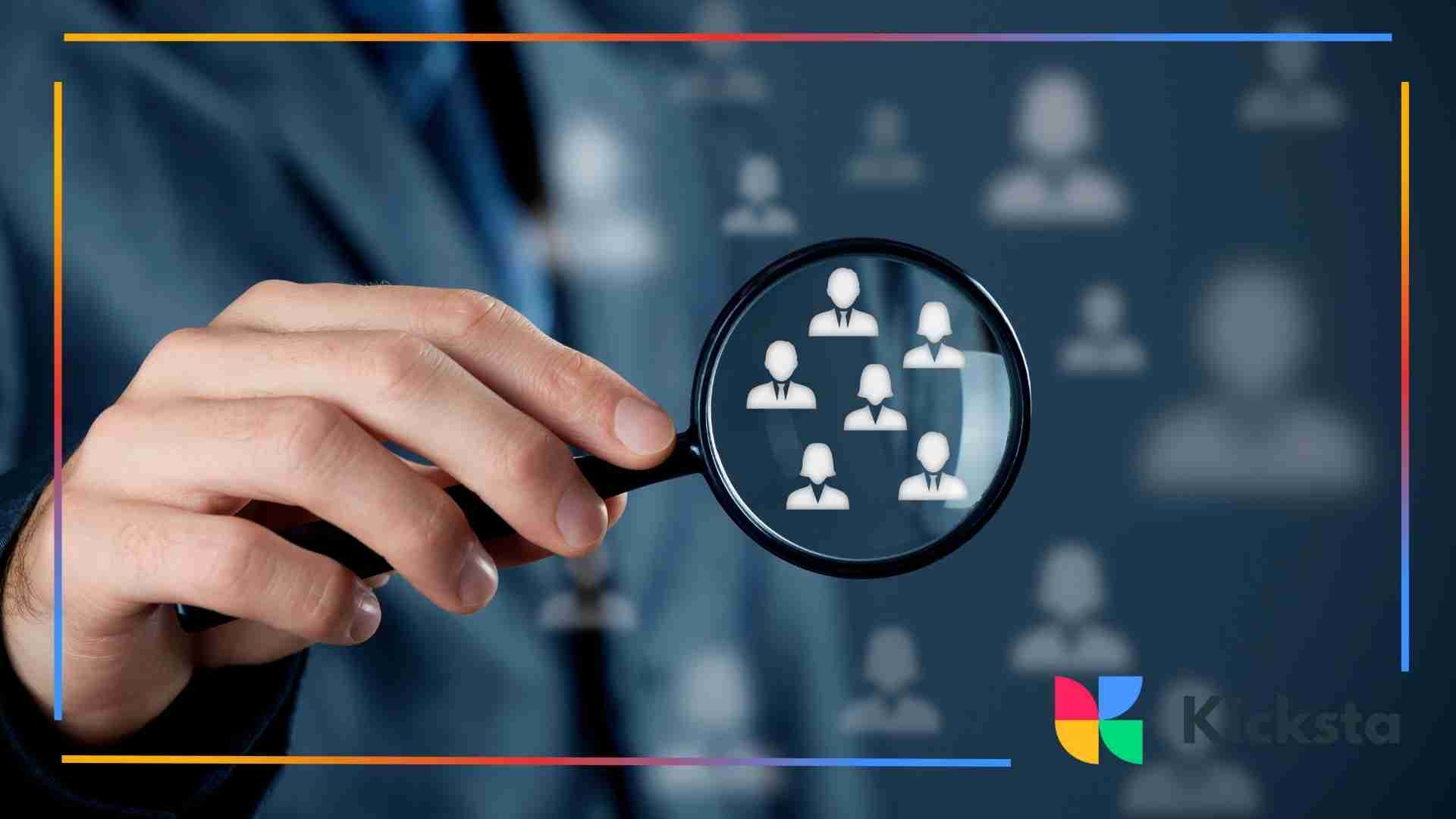 Person holding a magnifying glass over icons of people