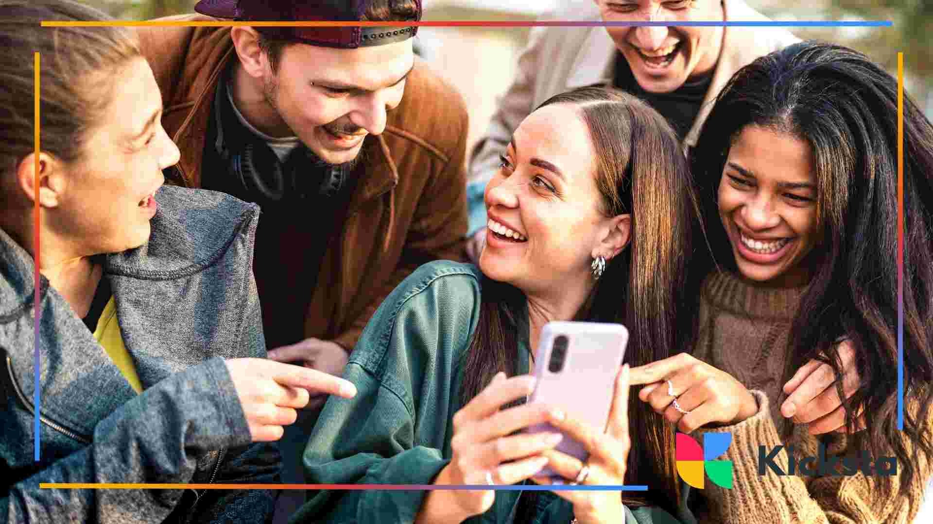 Group of friends laughing together while looking at a phone.