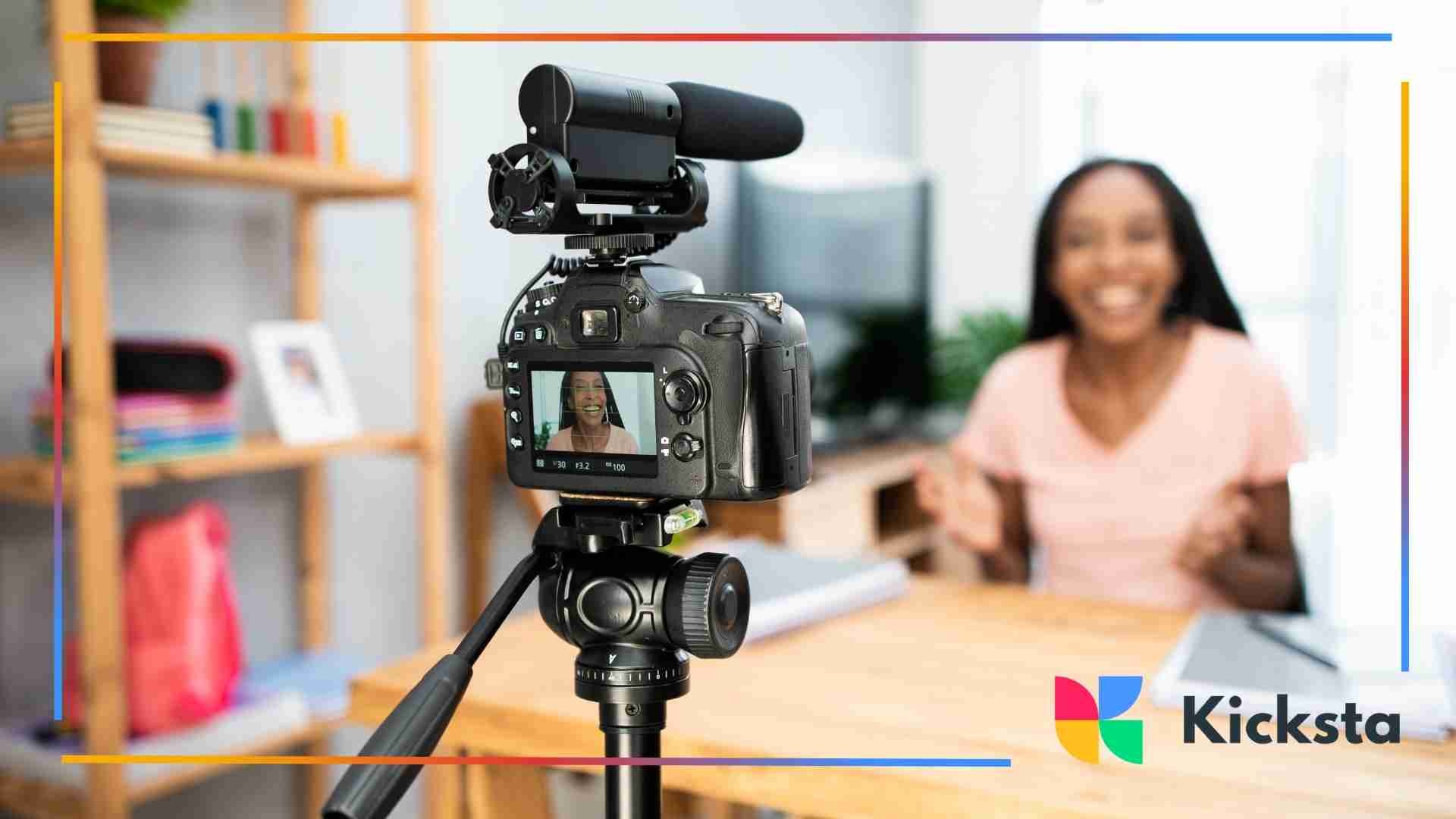Camera filming a woman smiling and talking at a desk.