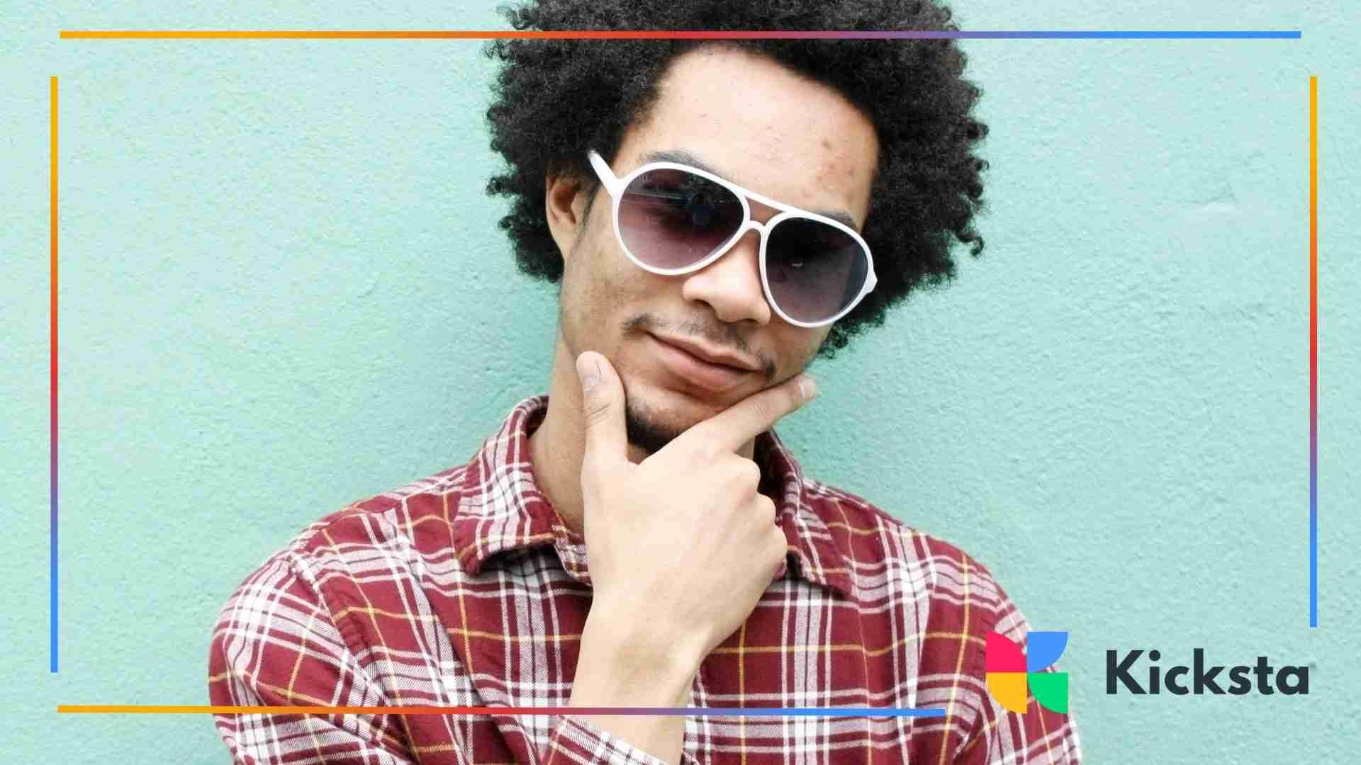 Man wearing a red plaid shirt and white sunglasses posing confidently.