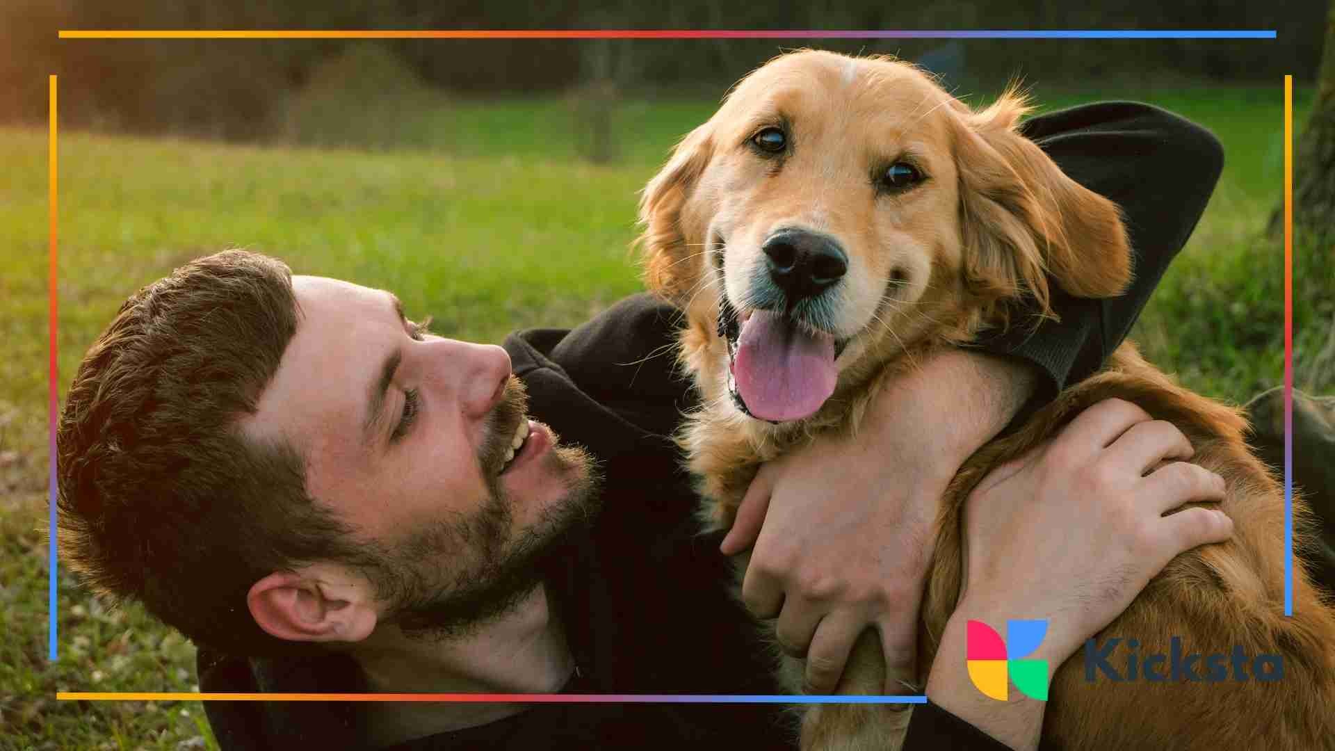 Man smiling and hugging a golden retriever outdoors.
