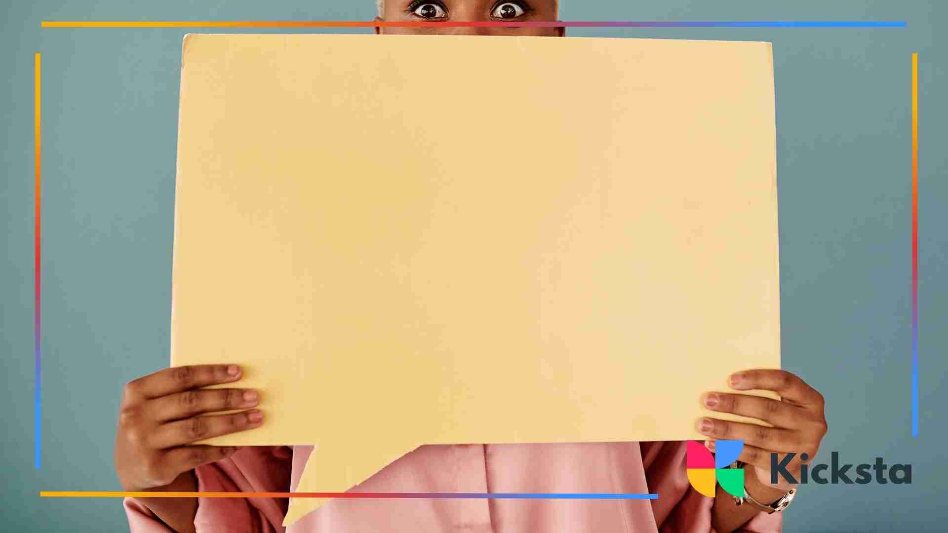 Person holding a large blank speech bubble sign in front of their face, with only their wide eyes visible above it.