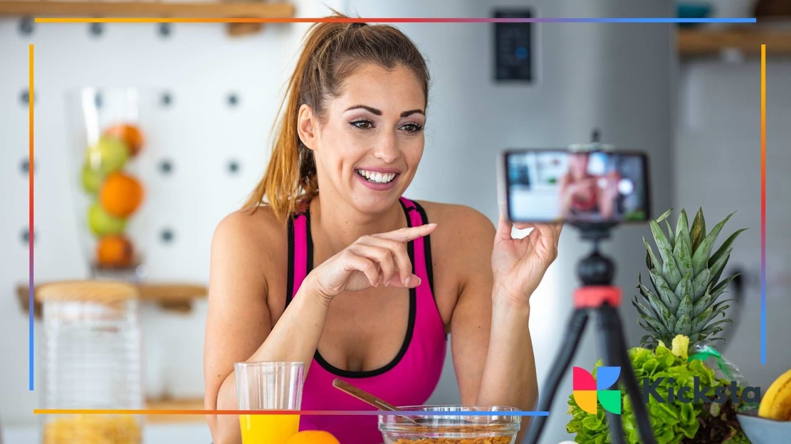 Fitness influencer filming healthy lifestyle vlog in kitchen with smartphone tripod, fresh fruits, and smoothie ingredients.