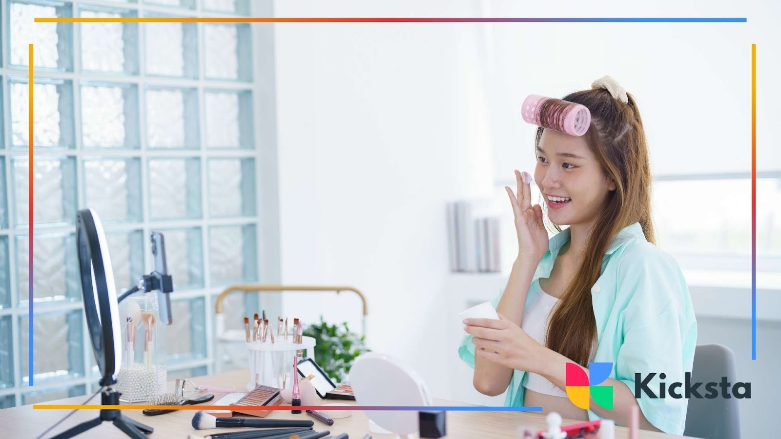 Beauty influencer filming skincare tutorial at vanity table with makeup products, ring light, and natural bright room setup.