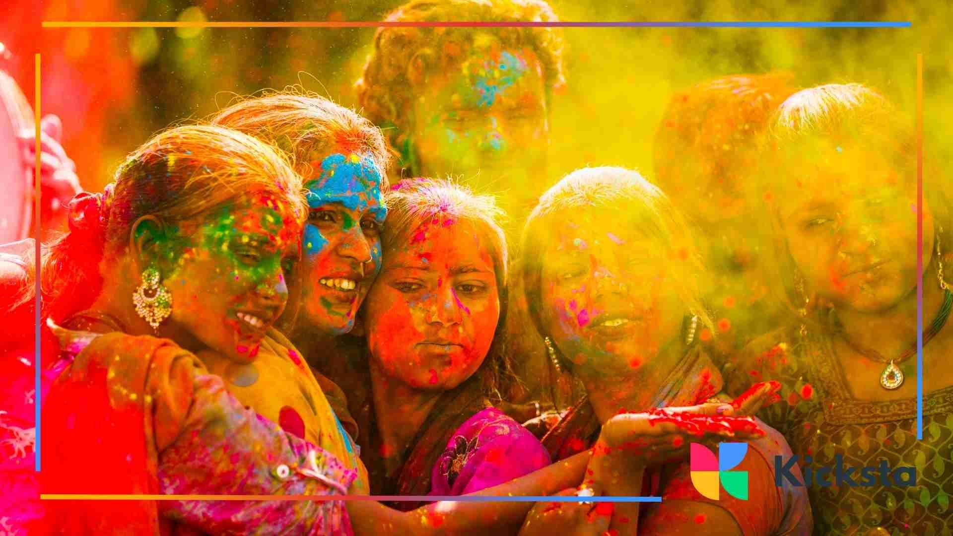 Group of women smiling and covered in colorful Holi powders, enjoying the festival with bright colors on their faces.