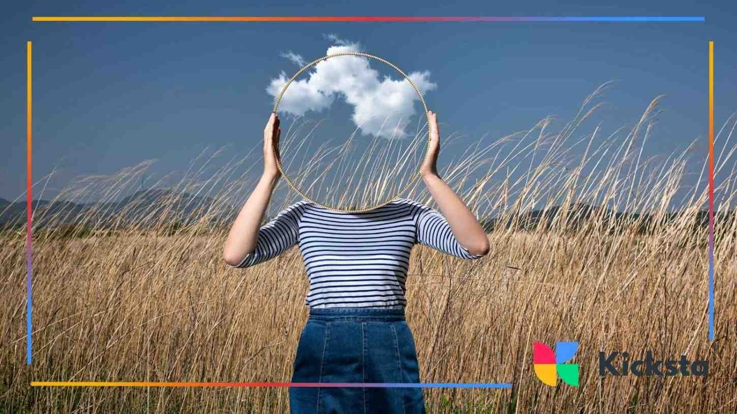 Creative photo of person holding round mirror in tall grass field, reflecting sky and clouds, representing creativity, imagination, and artistic content creation.