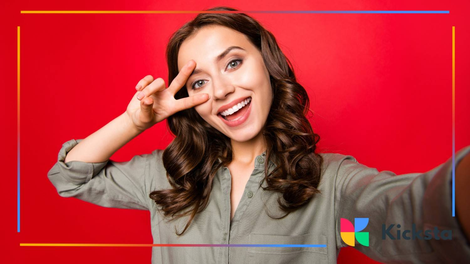 Smiling young woman taking a cheerful selfie against a bright red background.