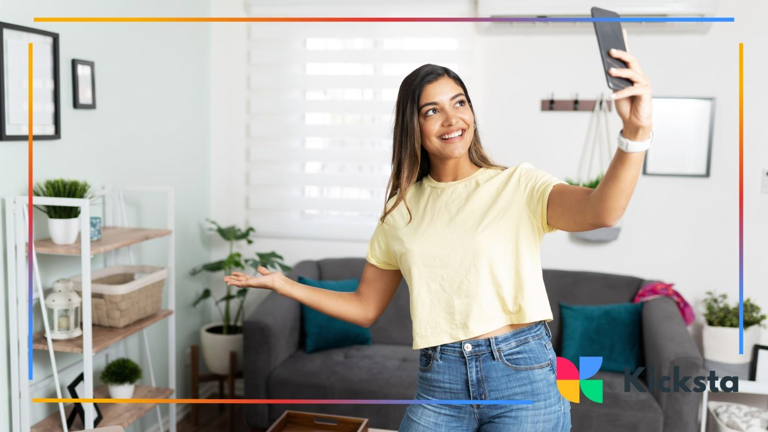 Happy woman recording a playful selfie video while standing in a cozy living room.