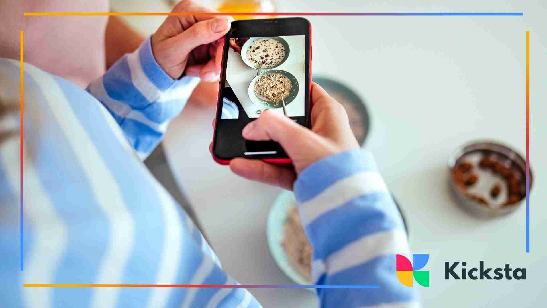 Person holding a smartphone overhead to take a photo of a bowl of cereal on a white table.