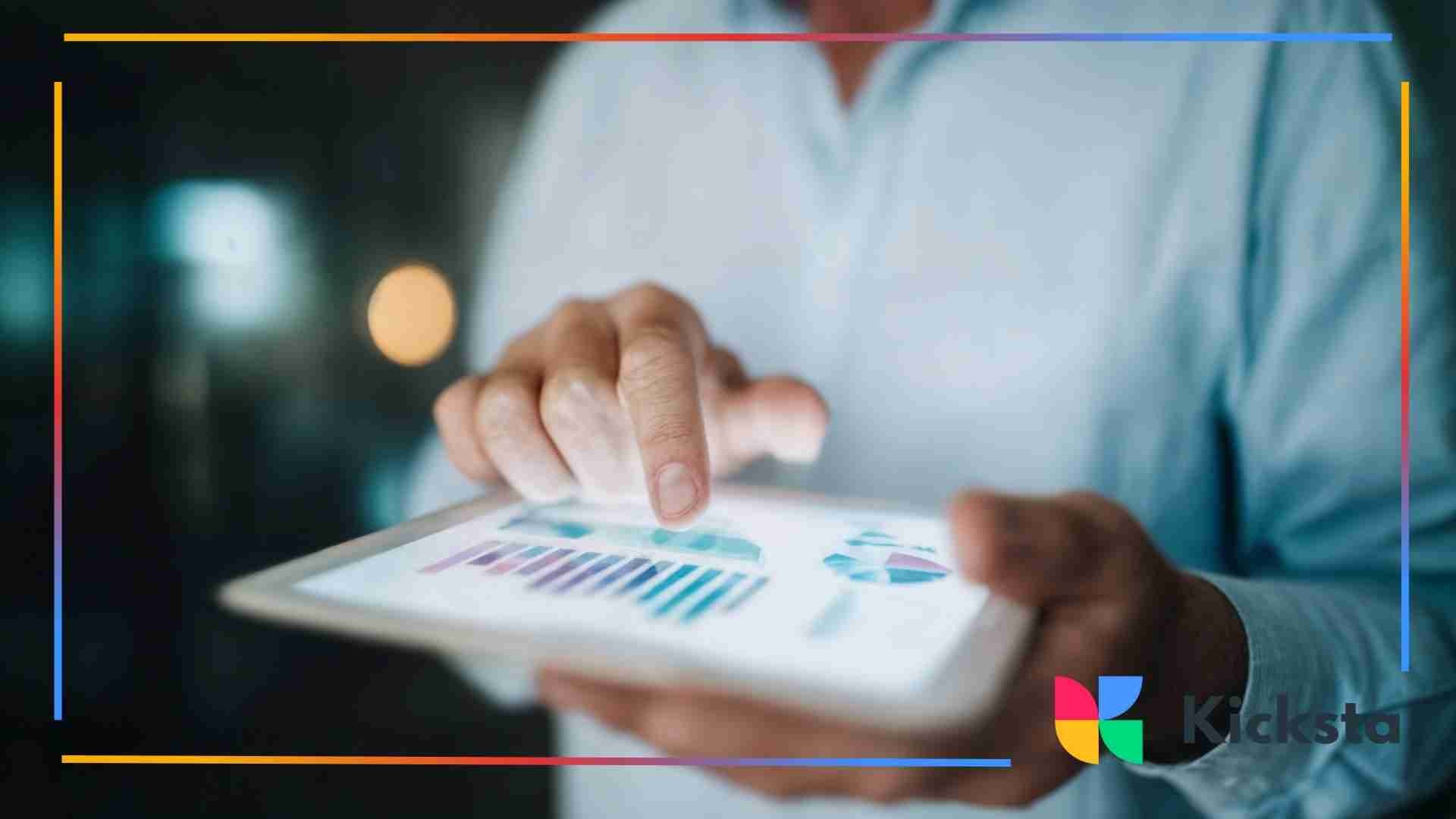 Close-up of a person’s hands tapping on a tablet screen displaying graphs and analytics.