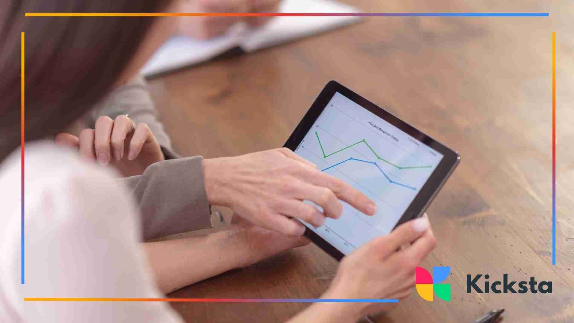 Close-up of two people reviewing a tablet screen displaying line graphs and website performance data during a meeting.