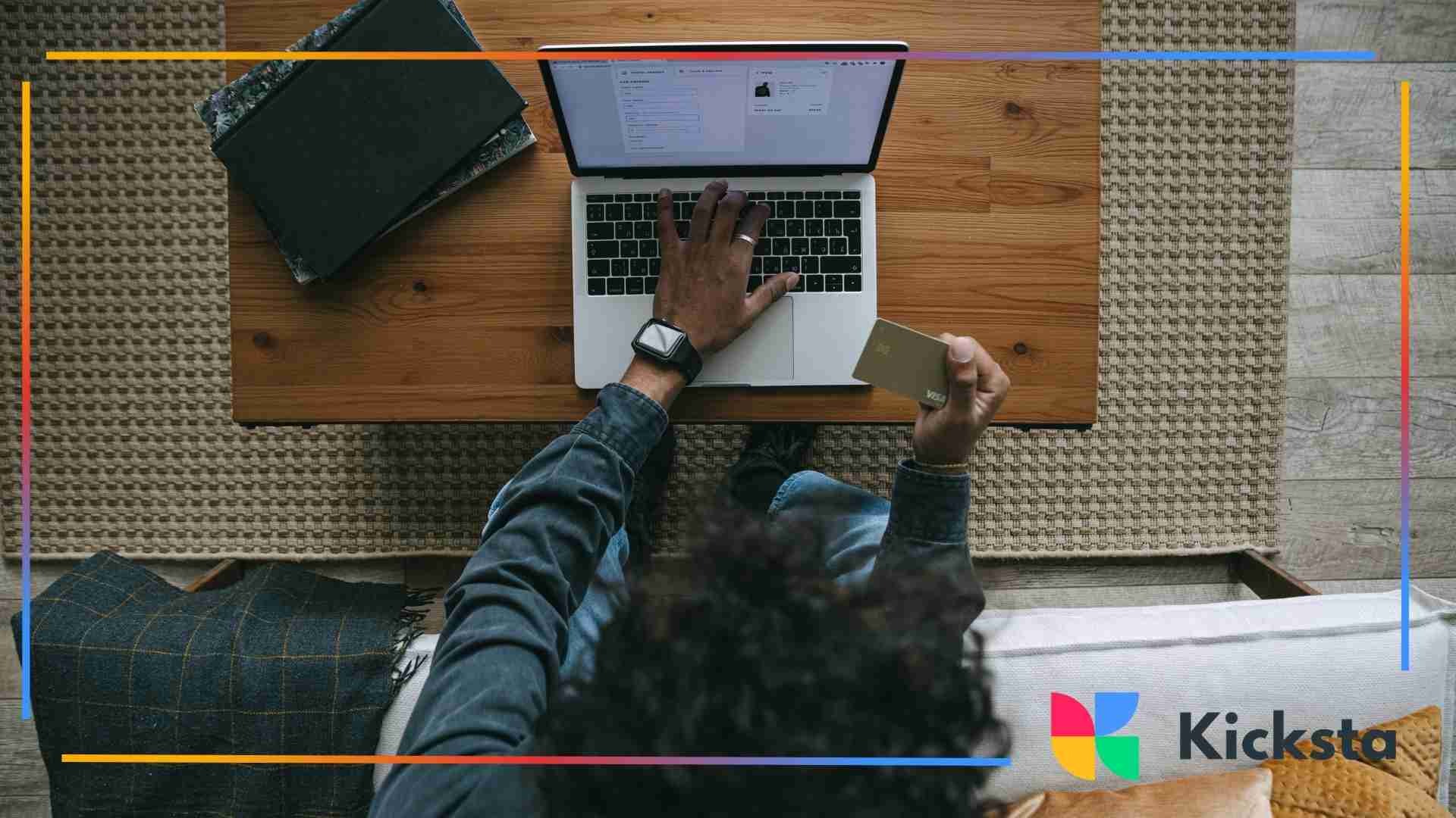 Overhead view of a person making an online purchase on a laptop while holding a credit card.