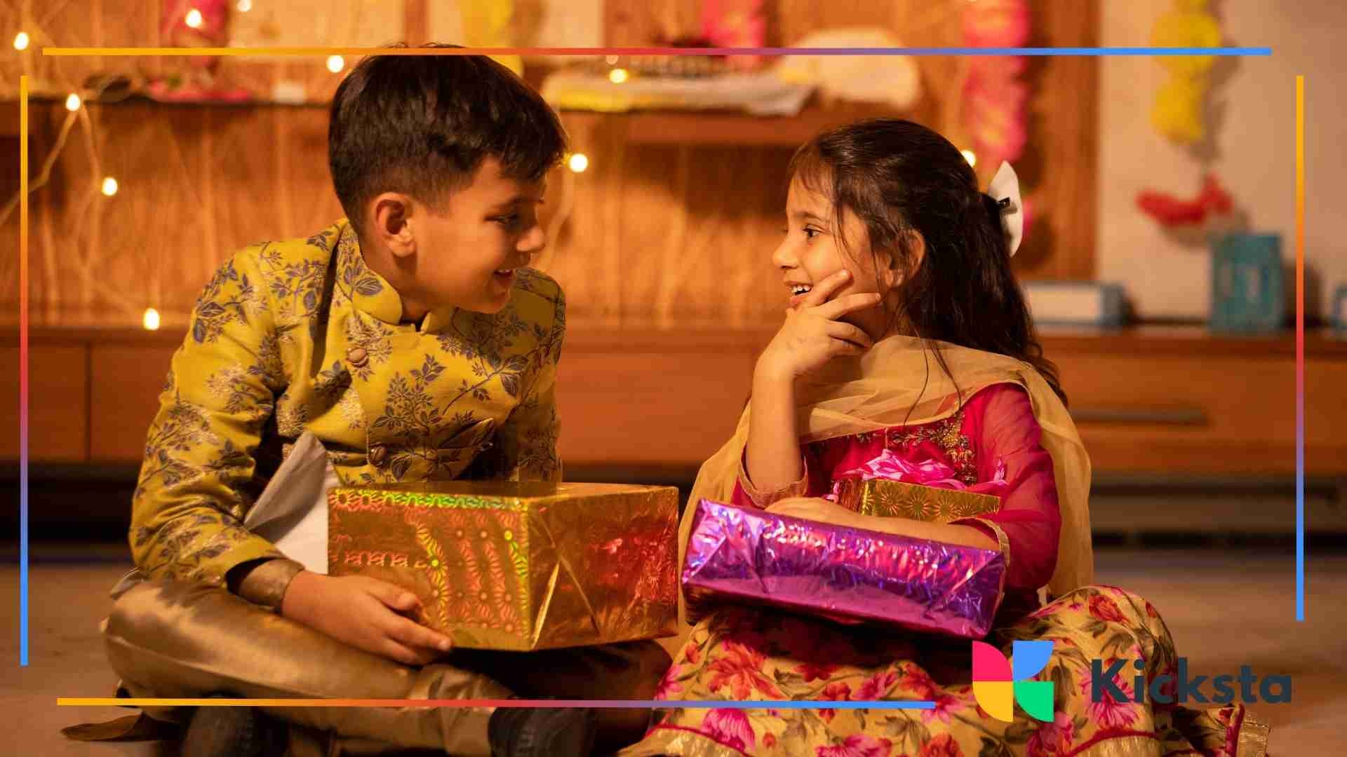 Two children in traditional festive clothing sitting on the floor and exchanging wrapped gifts while smiling at each other.