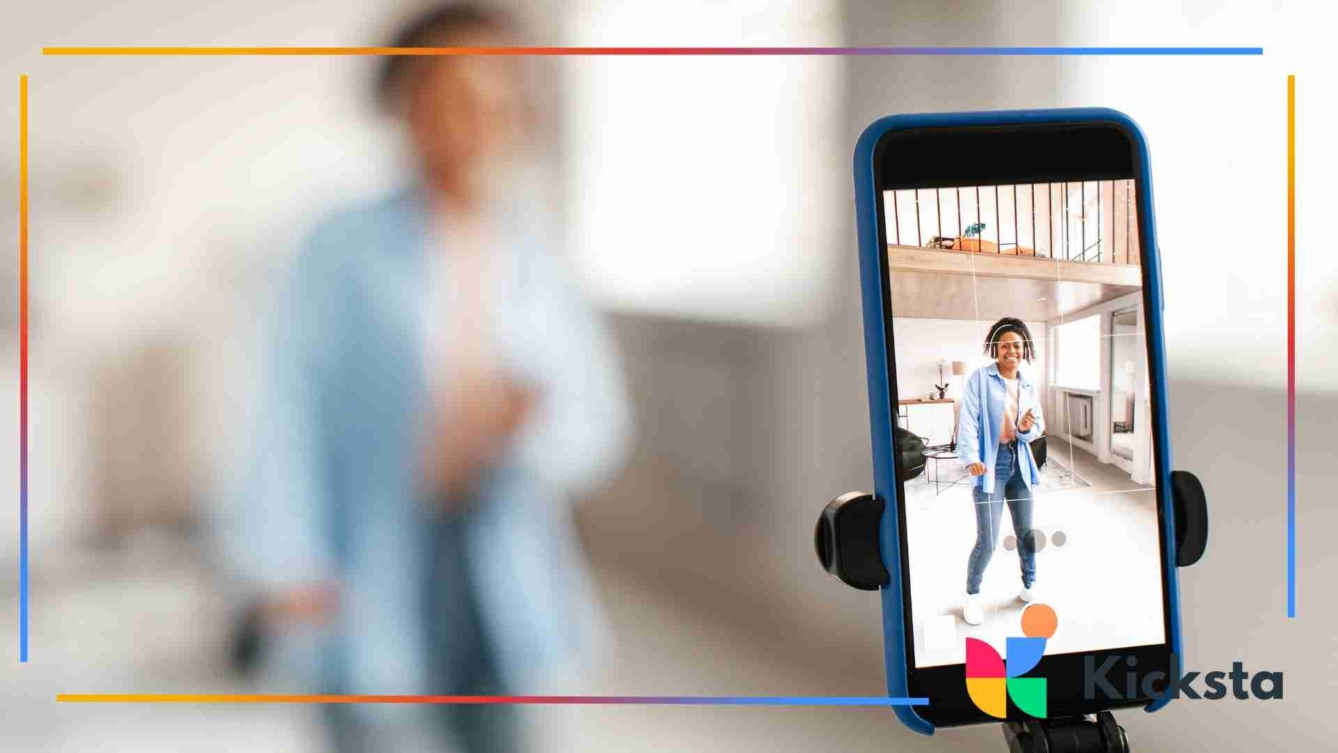 Smartphone on a tripod recording a woman posing indoors, with the camera screen showing her full body.